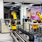Robotic arms in action within a modern industrial control room setting, showcasing technology and production.