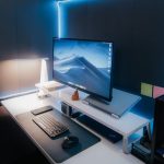 Organized workspace featuring a sleek monitor, keyboard, and ambient lighting for a tech-savvy environment.